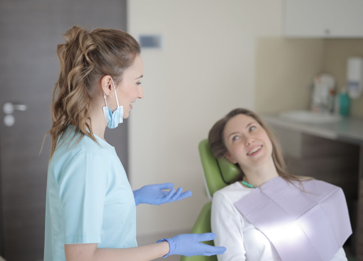 A patient calmly talking with a dentist in a bright consultation room while reviewing a treatment plan together