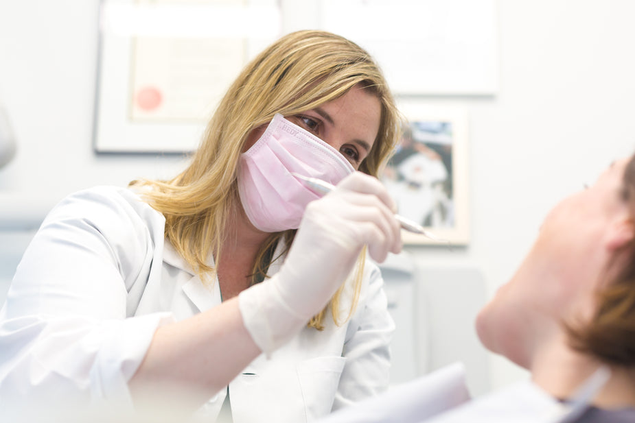 Dentist performing a routine dental checkup and reviewing a patients oral health during a consultation