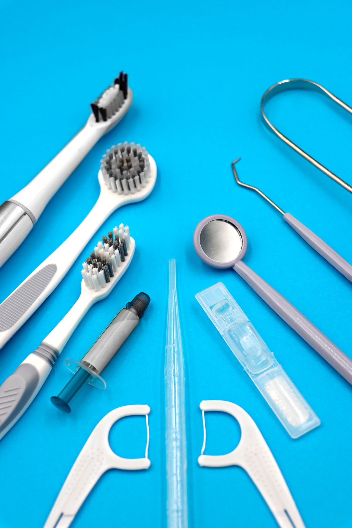 String floss, a set of small interdental brushes and a countertop water flosser laid out side by side on a bathroom counter