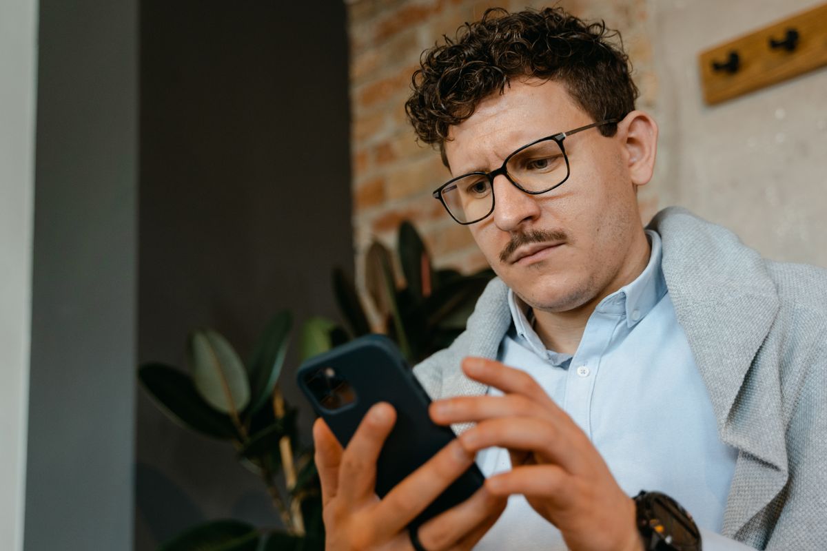 A person reading reviews on a smartphone with a skeptical expression