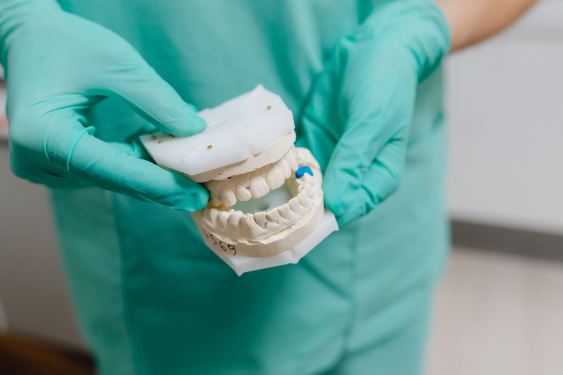 A dentist holding a plaster dental cast of the teeth
