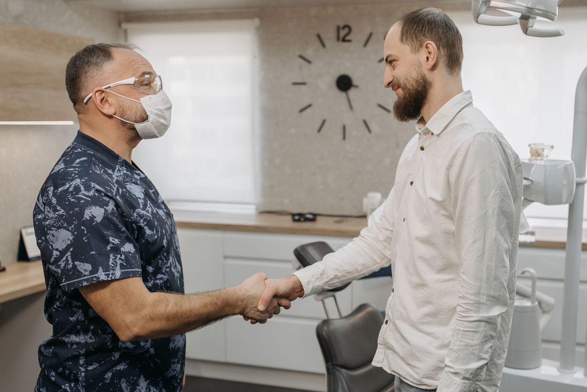 A dentist and patient shaking hands in a clinic, representing a trusted vetted dentist